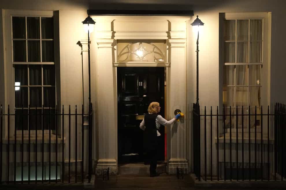 A woman polishes the door of no 11 Downing Street (PA)