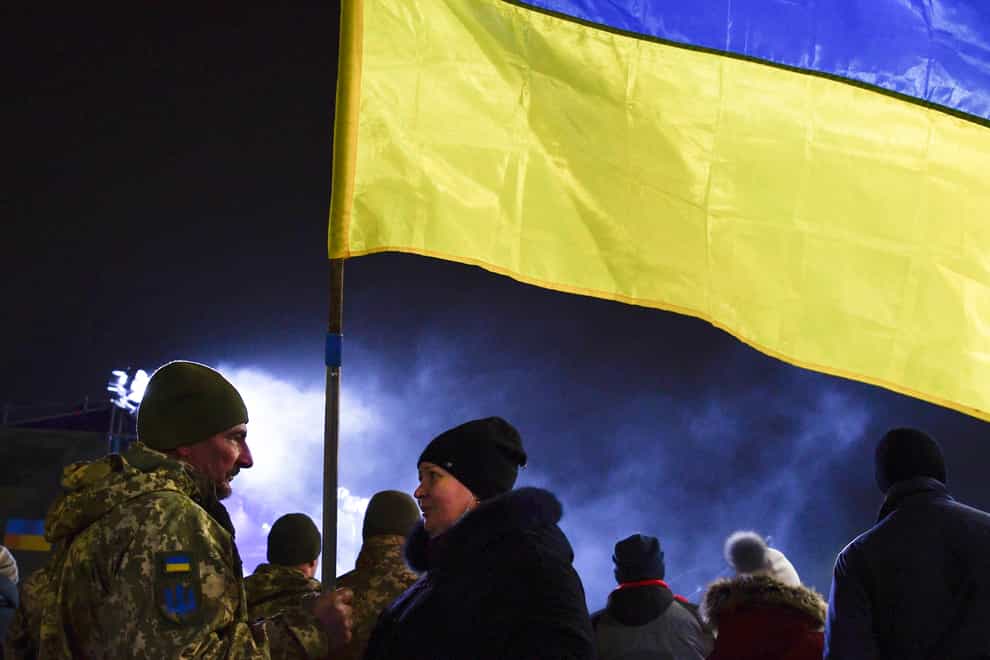 A Ukrainian serviceman speaks to a woman holding a Ukrainian national flag before a parade marking the Day of the Armed Forces of Ukraine in Kramatorsk (Andriy Andriyenko/AP)