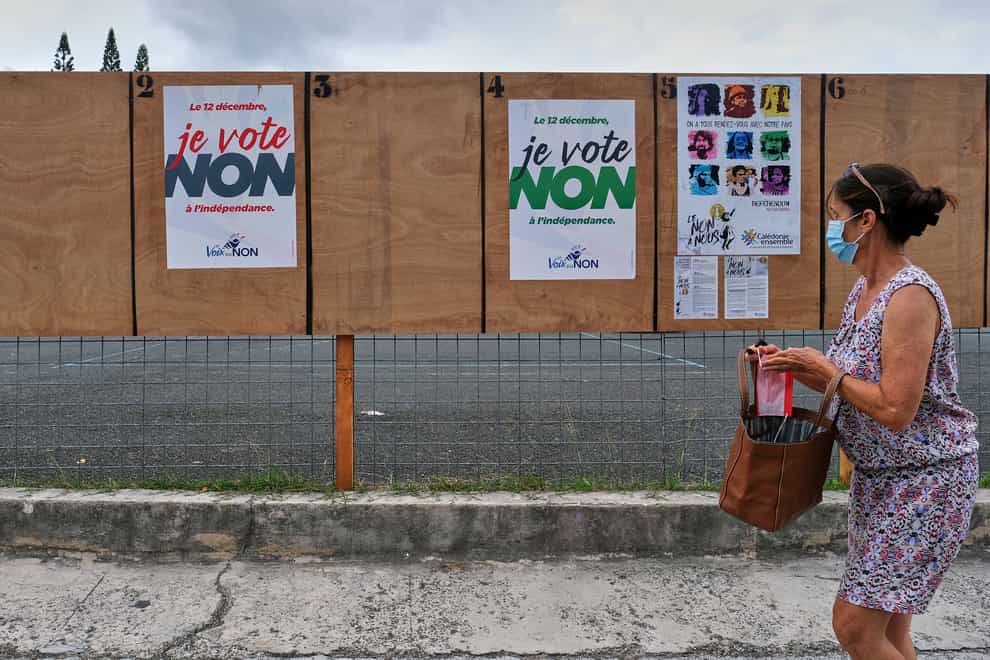 A woman walks past electoral posters calling for a No vote in the referendum in New Caledonia (Clotilde Richalet/AP)