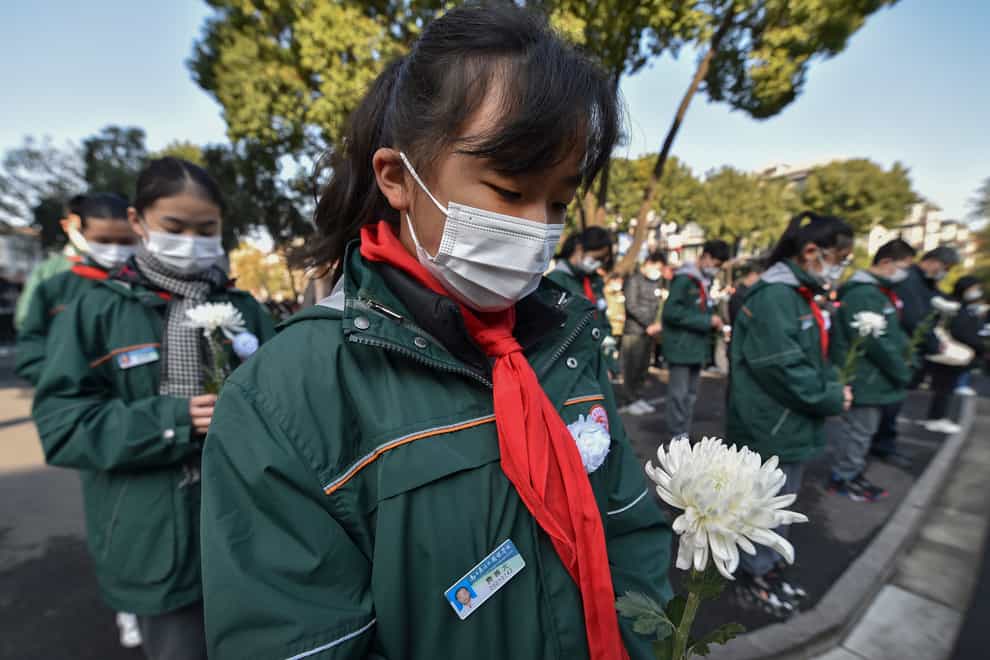 Students wearing face masks hold flowers mourn for the victims of the Nakjing Massacre at a mass burial site during the annual commemoration of the 1937 Nanking Massacre in Nanjing in eastern China’s Jiangsu province, Monday, Dec. 13, 2021. China on Monday marking the 84th anniversary of the Nanking Massacre, in which it says hundreds of thousands of civilians and disarmed soldiers were killed by Japanese soldiers in and around the former Chinese capital. (Chinatopix Via AP)