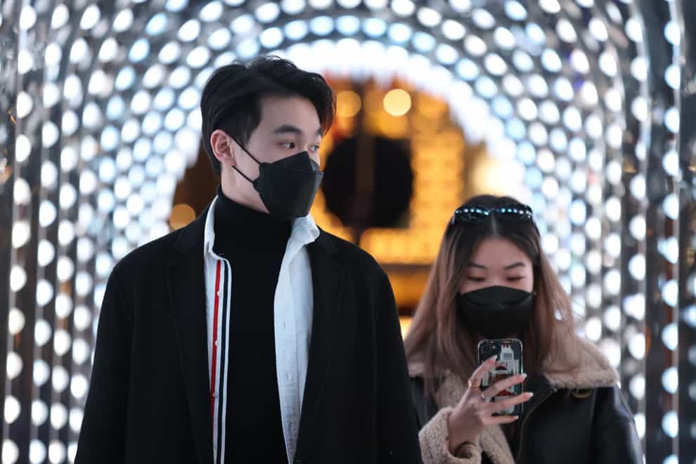 People wearing face masks walk through a Christmas-themed arch in Covent Garden (James Manning/PA)