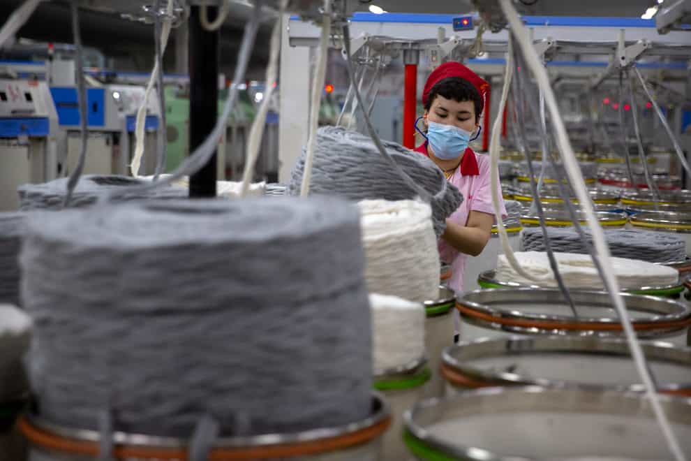 A worker gathers cotton yarn at a textile manufacturing plant, in Aksu in western China’s Xinjiang Uyghur Autonomous Region (Mark Schiefelbein/AP)