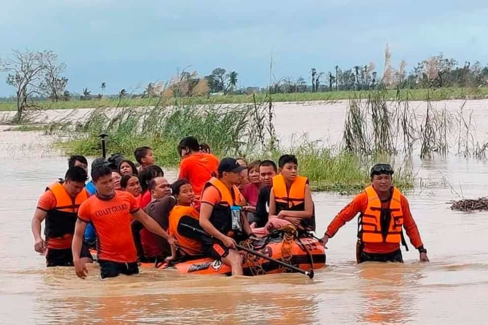 In this photo provided by the Philippine Coast Guard, rescuers pull a rubber boat as they assist residents who were trapped in their homes after floodwaters caused by Typhoon Rai inundated their village in Loboc, Bohol, central Philippines on Friday, Dec. 17, 2021. The strong typhoon engulfed villages in floods that trapped residents on roofs, toppled trees and knocked out power in southern and central island provinces, where more than 300,000 villagers had fled to safety before the onslaught, officials said. (Philippine Coast Guard via AP)