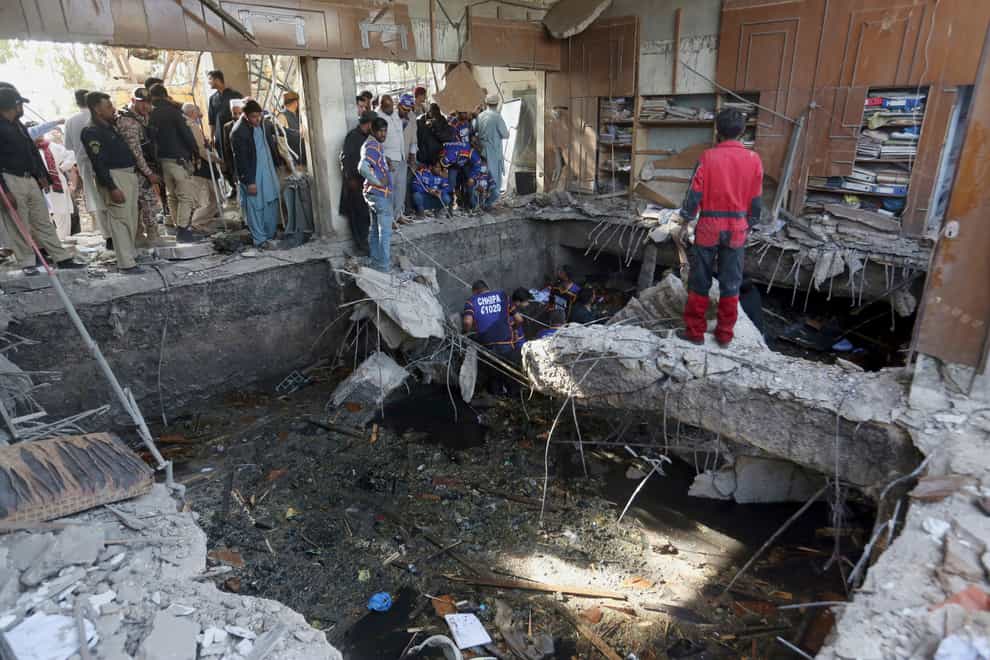 Rescuers inspect the scene of a gas explosion in Karachi, Pakistan, Saturday, Dec. 18, 2021. The powerful gas explosion in a sewage system in the southern Pakistan city killing several people and wounding others Saturday, police and a health official said. (AP Photo/Fareed Khan)