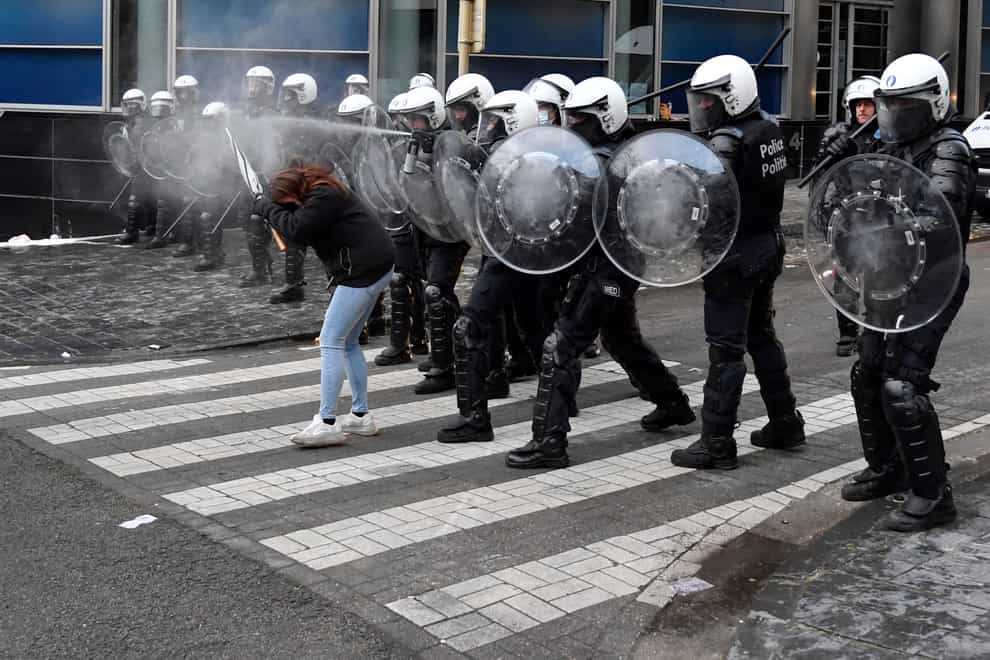 A police officer uses pepper spray during a protest against coronavirus measures in Brussels, Belgium, on December 5 (Geert Vanden Wijngaert/AP)