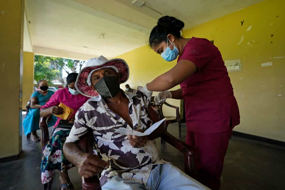 A Sri Lankan man receives his third dose of Covid-19 vaccine from a health worker in Colombo, Sri Lanka (Eranga Jayawardena/AP)