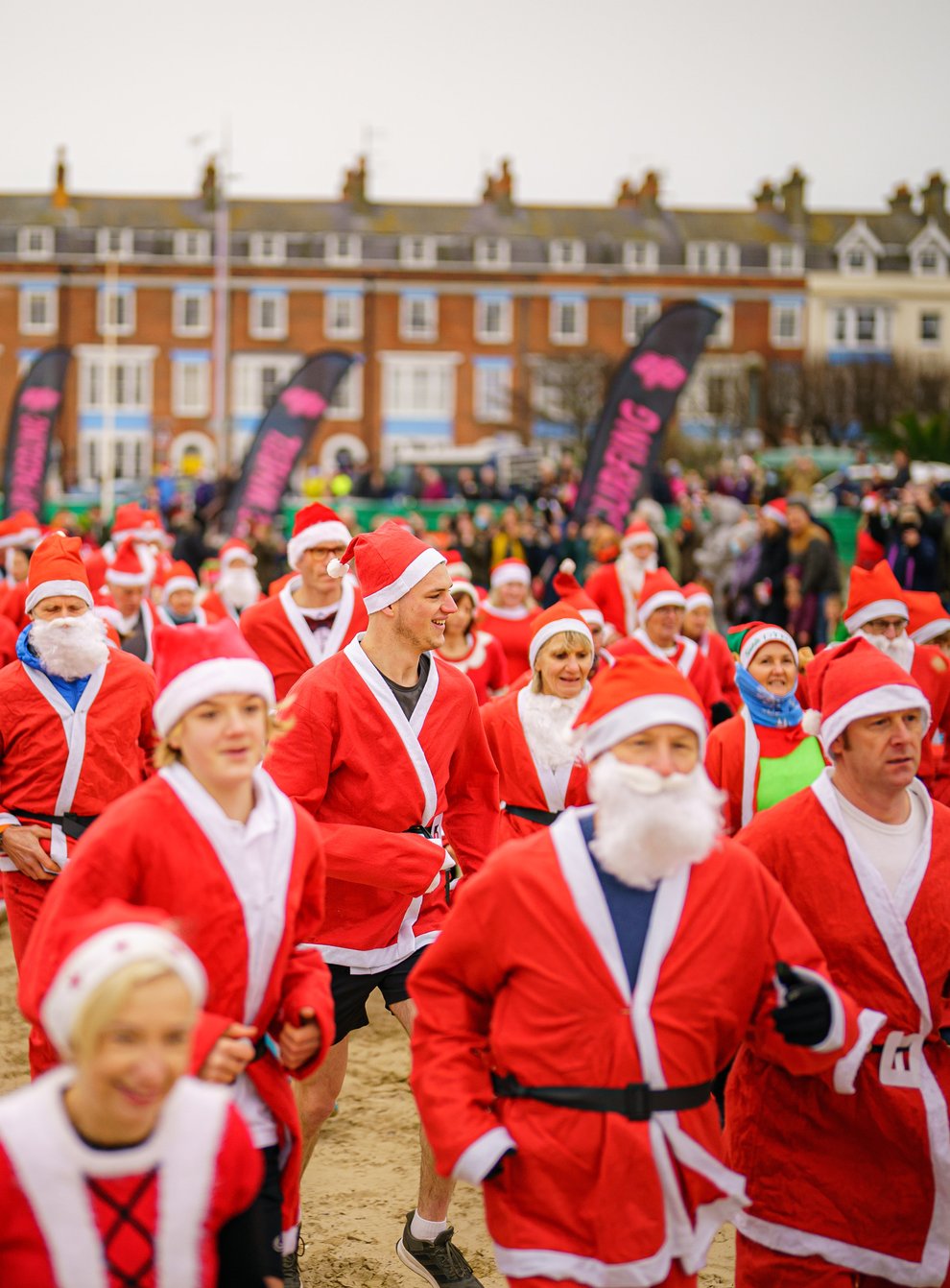 People dressed as Santa make their way along Weymouth beach (Ben Birchall/PA)