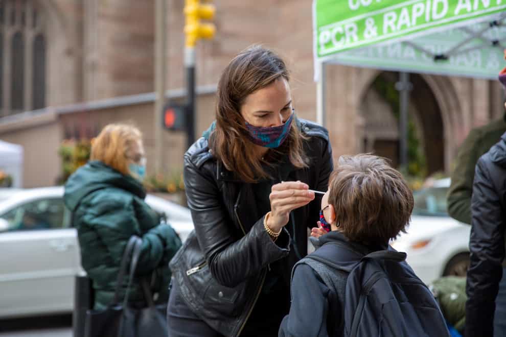 Katie Lucey administers a Covid-19 test on her son Maguire on Wall Street in New York (AP Photo/Ted Shaffrey)