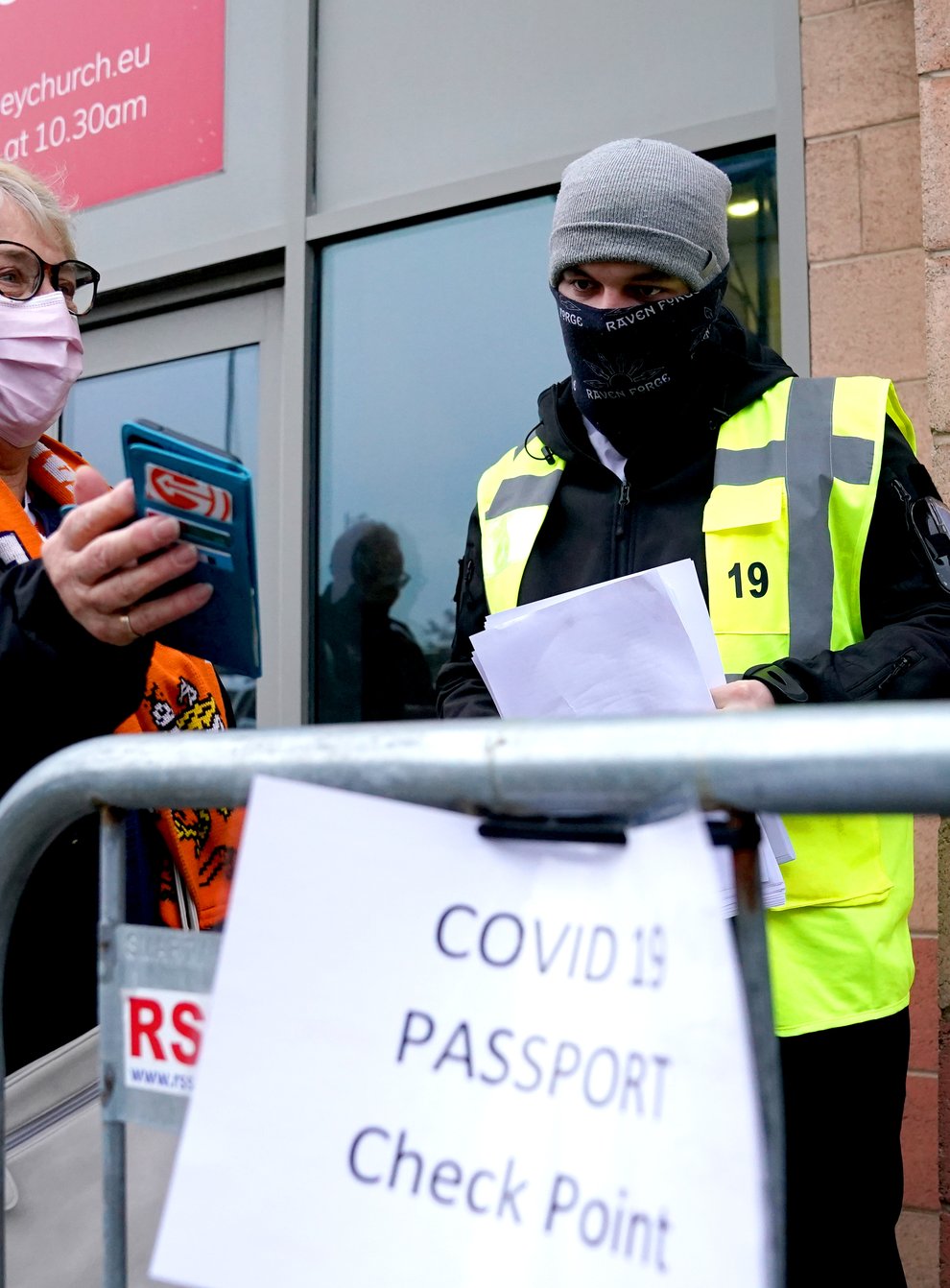 A Blackpool fan shows their Covid pass to a member of security staff at the Covid 19 passport check point ahead of the Sky Bet Championship match in Blackpool. (Martin Rickett/ PA)