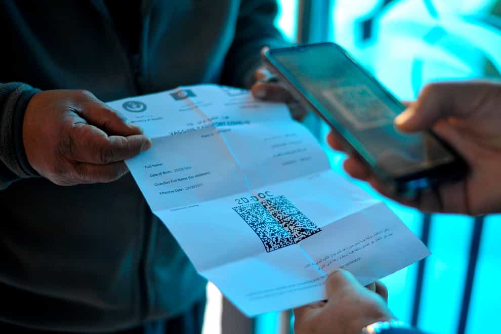 A man displays his vaccine passport before being allowed into a government office in Tunis (Hassene Dridi/AP)