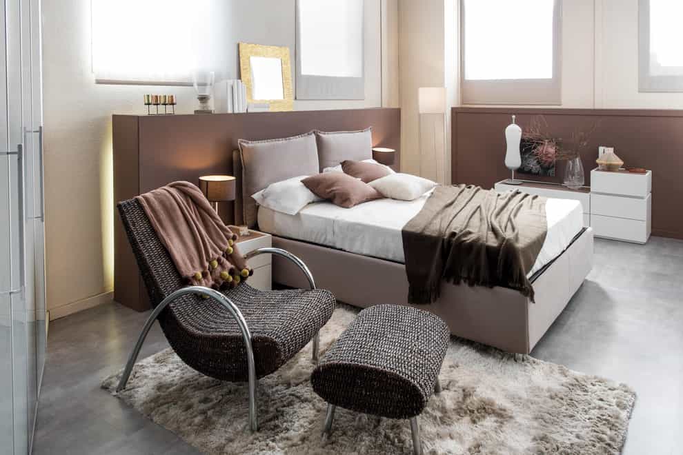 Modern luxury bedroom with recliner chair, double bed with large headboard and cabinets (Alamy/PA)