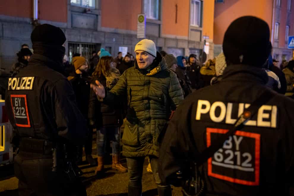 Police officers speak to demonstrators at a protest against Covid restrictions in Munich (Lennart Preiss/dpa via AP)