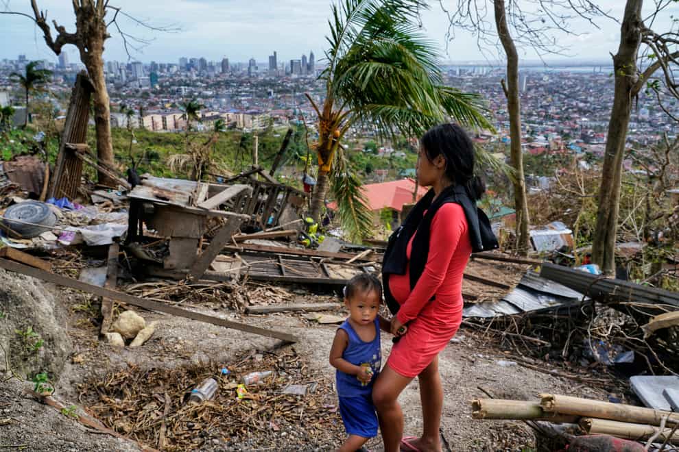 Alona Nacua, right, stands beside her son as she looks at their damaged house due to Typhoon Rai in the Philippines (AP Photo/Jay Labra)