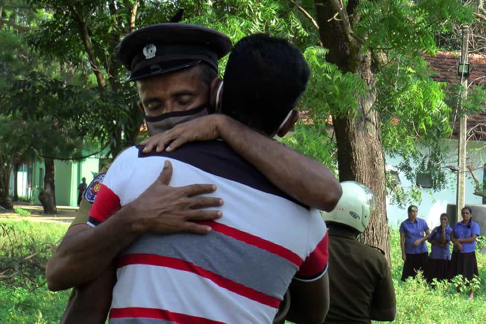 A Sri Lankan police officer consoles a relative of a victim of the shooting (Achala Pussalla/AP)