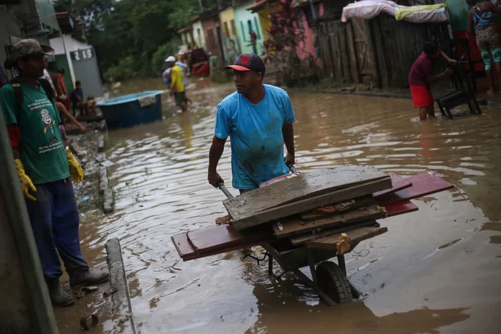 Residents clean out their flooded homes in Itapetinga, Bahia state, Brazil (Raphael Muller/AP)