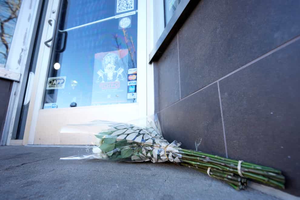 Bouquets of flowers lie outside a tattoo shop which was the scene of one of the shootings (AP Photo/David Zalubowski)