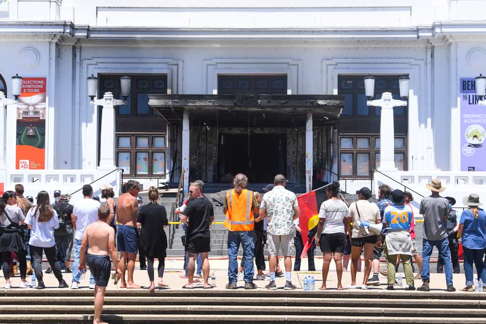 People stand in front of the fire-damaged Old Parliament House in Canberra (Lukas Coch/AAP Image via AP)