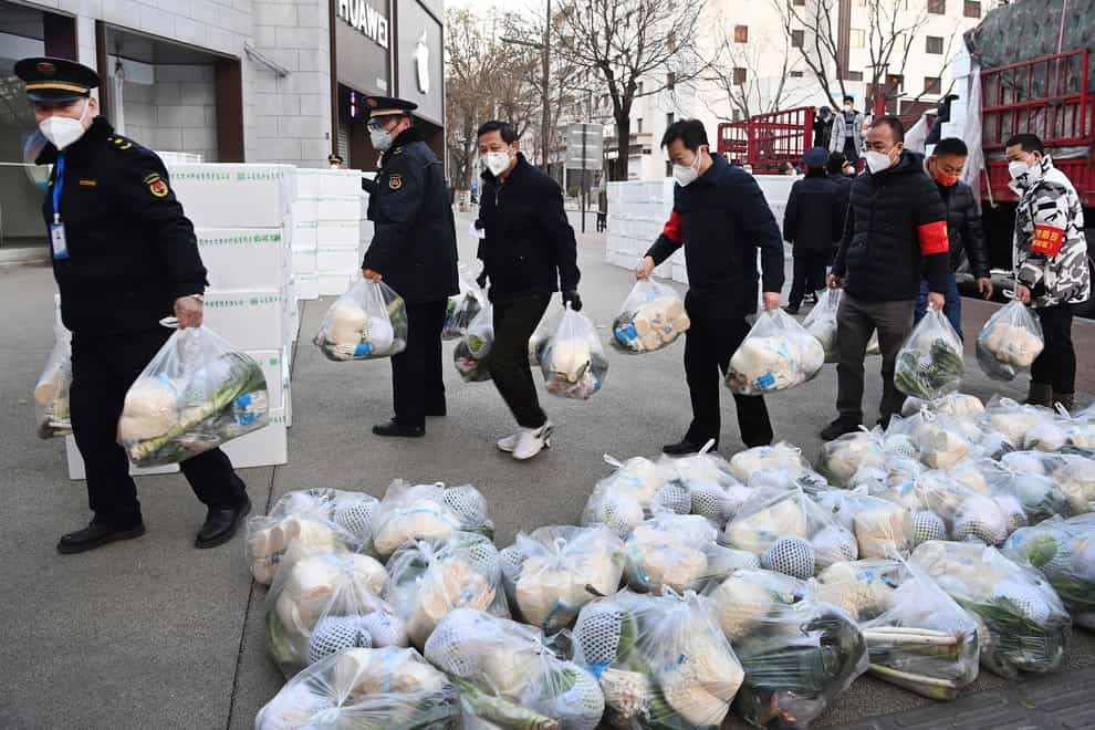 Volunteers and local officials deliver groceries to an apartment building in Xi’an (Liu Xiao/Xinhua via AP)