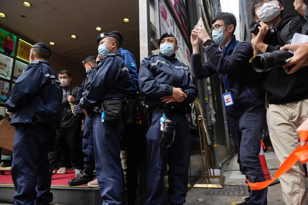 Police officers stand guard as journalists take photos outside the office of Stand News in Hong Kong (Vincent Yu/AP)