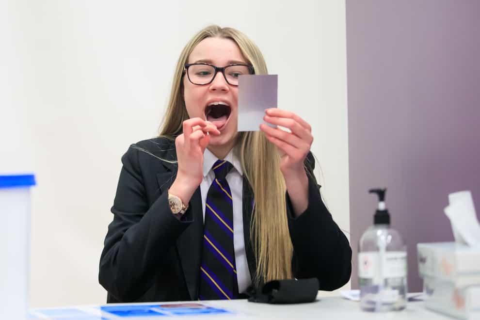 Erin Horn looking in a mirror while taking a Lateral Flow Test as children arrive at Outwood Academy in Woodlands, Doncaster in Yorkshire (Danny Lawson/PA)
