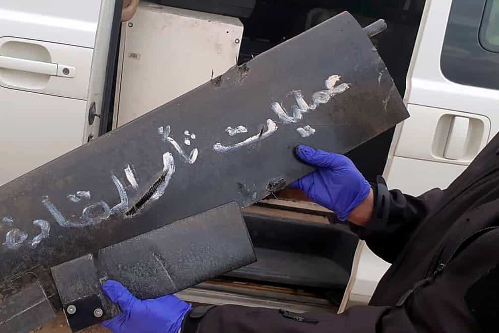 A security official holds part of the wreckage of a drone with Arabic that reads, ‘revenge operations for our leaders’ at Baghdad airport (International Coalition via AP)