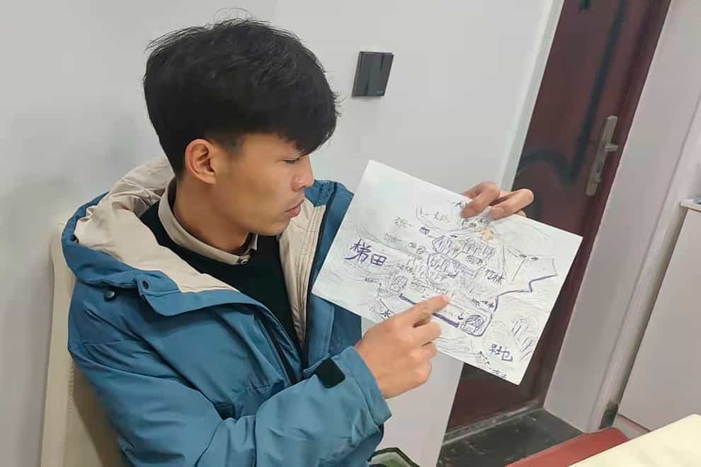 Li Jingwei points to a detailed map he drew from memory of his childhood village as he sits in Lankao in central China’s Henan Province (Li Jingwei via AP)