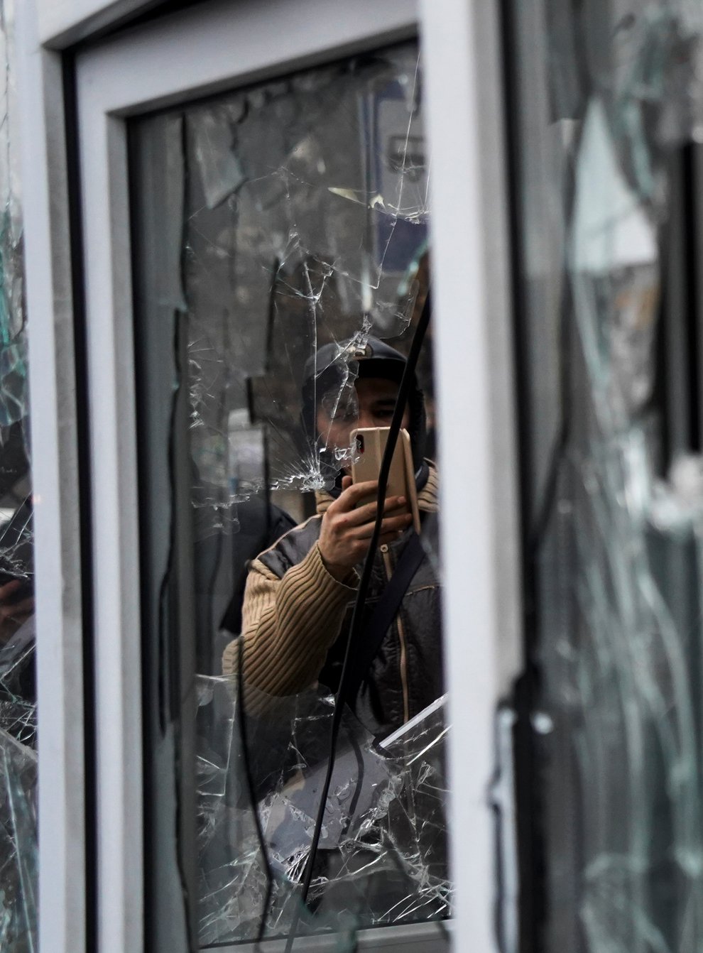 A man takes a photo of windows of a police kiosk damaged by demonstrators during a protest in Almaty, Kazakhstan (AP)