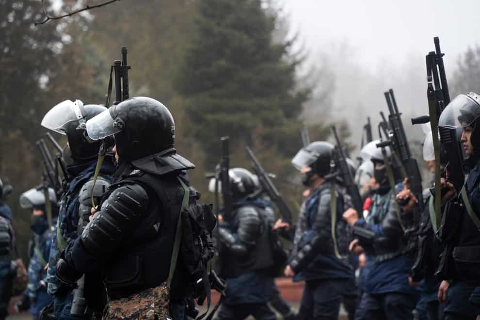 Riot police officers hold their weapons ready at a demonstration in Almaty on Wednesday (AP)