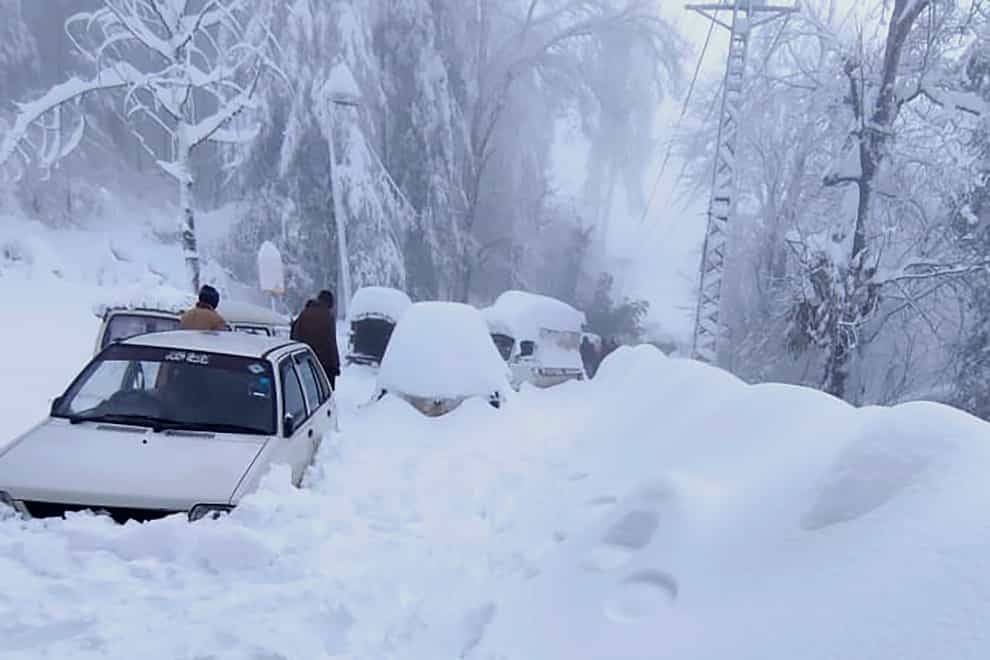 People walk past vehicles trapped in heavy snow in Murree (Inter Services Public Relations via AP)
