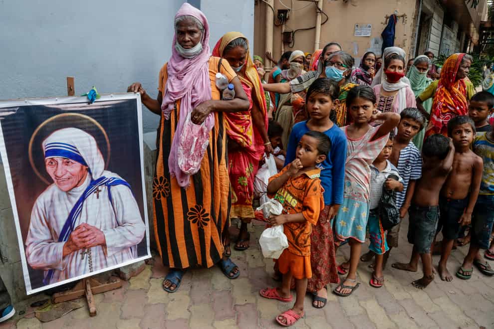 Homeless people gather beside a portrait of Saint Teresa (AP)