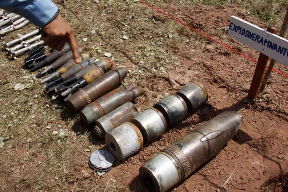 A Cambodian demining expert points to unexploded bombs displayed on the ground before a destruction ceremony in Preah Vihear province (Heng Sinith/AP)
