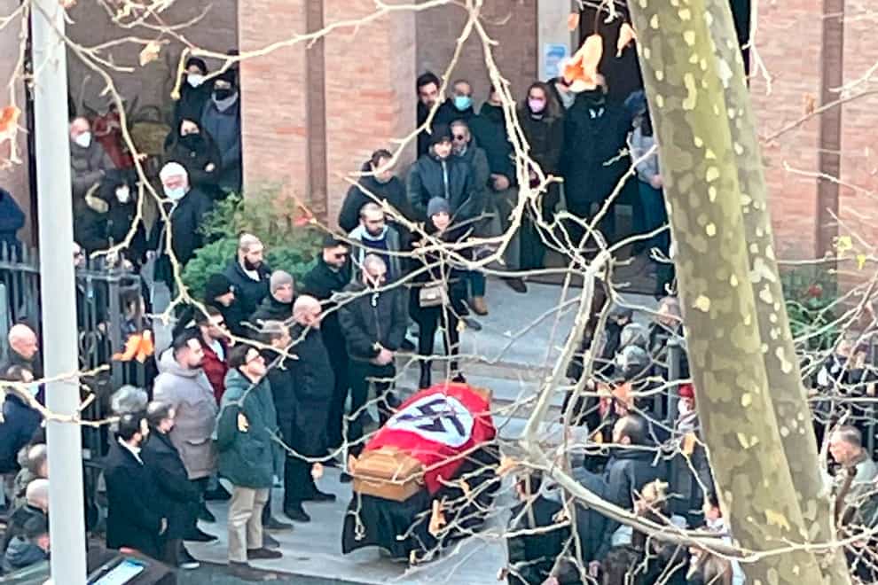 A picture made available by the Italian online news portal Open, showing people gathered around a swastika-covered casket outside the St. Lucia church, in Rome, Monday, Jan. 10, 2022. The Catholic Church in Rome on Tuesday, Jan. 11, 2022, strongly condemned as “offensive and unacceptable” a funeral procession outside a church in which the casket was draped in a Nazi flag and mourners gave the fascist salute. (Open Via AP)