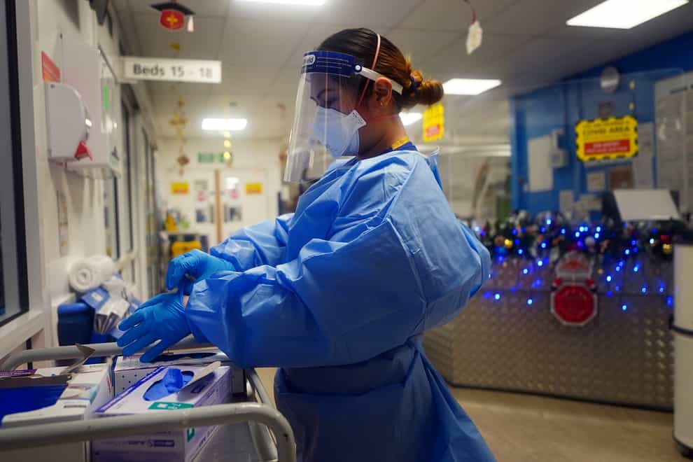 A nurse puts on PPE on a ward for Covid-19 patients at King’s College Hospital in south-east London (Victoria Jones/PA)
