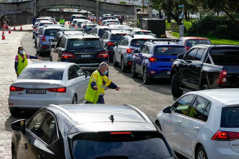 Traffic marshalls direct cars at a drive-through Covid-19 testing clinic at Bondi Beach in Sydney, Australia (Mark Baker/AP)