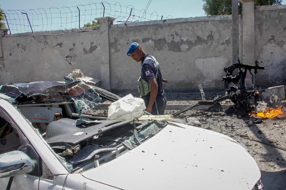 A Somali policeman looks at a destroyed vehicle at the scene of a blast in Mogadishu, Somalia Wednesday, Jan. 12, 2022. A large explosion was reported outside the international airport in Somalia’s capital on Wednesday and an emergency responder said there were deaths and injuries. (AP Photo/Farah Abdi Warsameh)