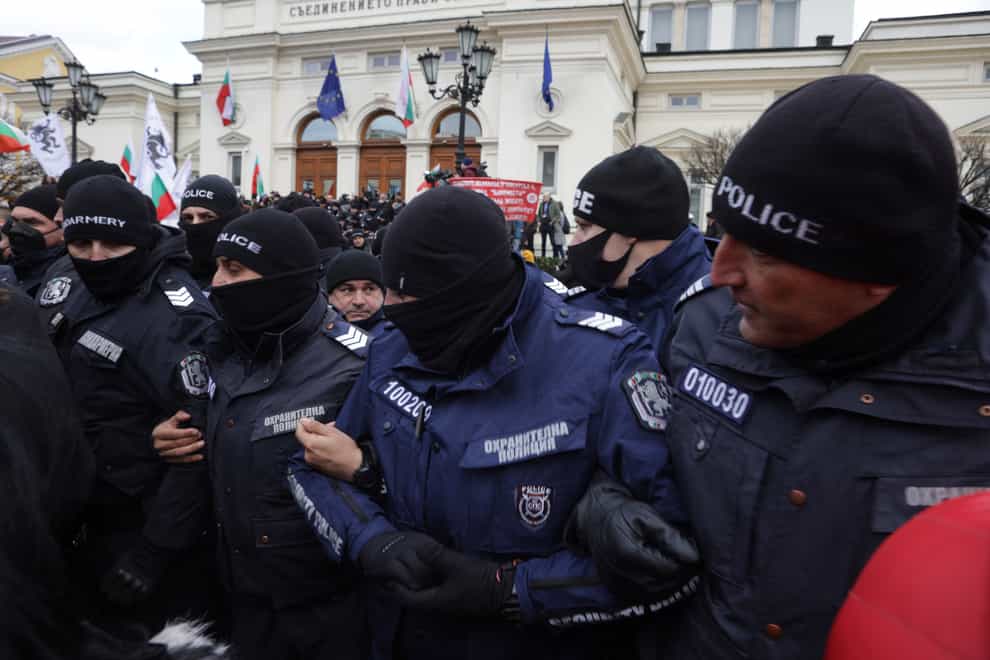 Police officers try to keep protesters away from the Bulgarian Parliament building in Sofia, Wednesday, Jan. 12, 2022. Protesters opposing COVID-19 restrictions in Bulgaria have clashed with police as they were trying to storm the Parliament in Sofia. Heavy police presence prevented protesters from entering the building and some were detained. (AP Photo/Valentina Petrova)