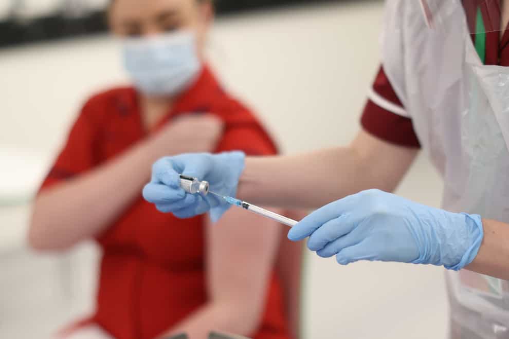 A nurse practitioner fills a needle with the Covid-19 vaccine before administering it to Sister Joanna Sloan (left), the first person in Northern Ireland to receive the first of two Pfizer/BioNTech Covid-19 vaccine jabs, at the Royal Victoria Hospital, in Belfast, on the first day of the largest immunisation programme in the UK’s history. Care home workers, NHS staff and people aged 80 and over will begin receiving the jab from Tuesday.