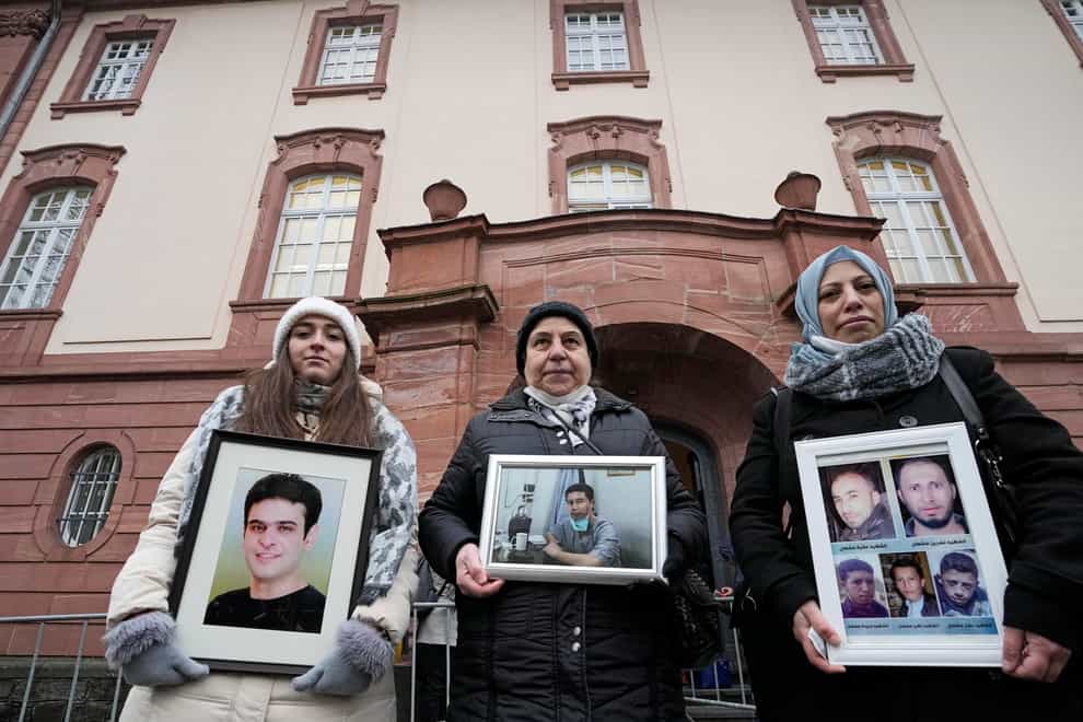 From left, Syrian women Samaa Mahmoud, Mariam Alhallak and Yasmen Almashan hold pictures of relatives who died in Syria, before the verdict in front of the court in Koblenz, Germany (Martin Meissner/AP)