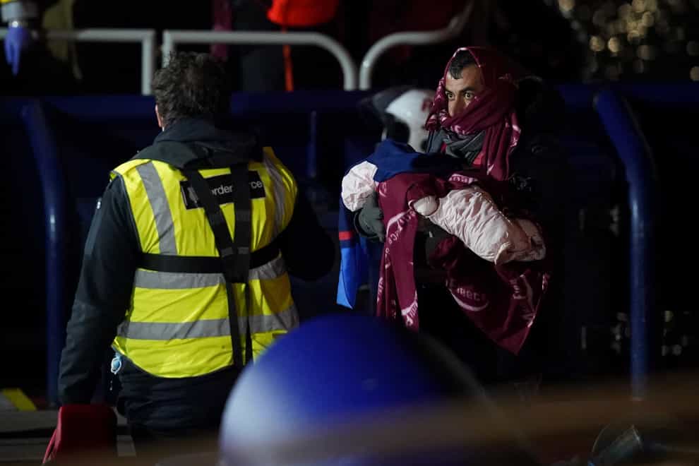 A man carries a baby as a group of people thought to be migrants are brought in to Dover, Kent, after being rescued by the RNLI following a small boat incident in the Channel (Gareth Fuller/PA)