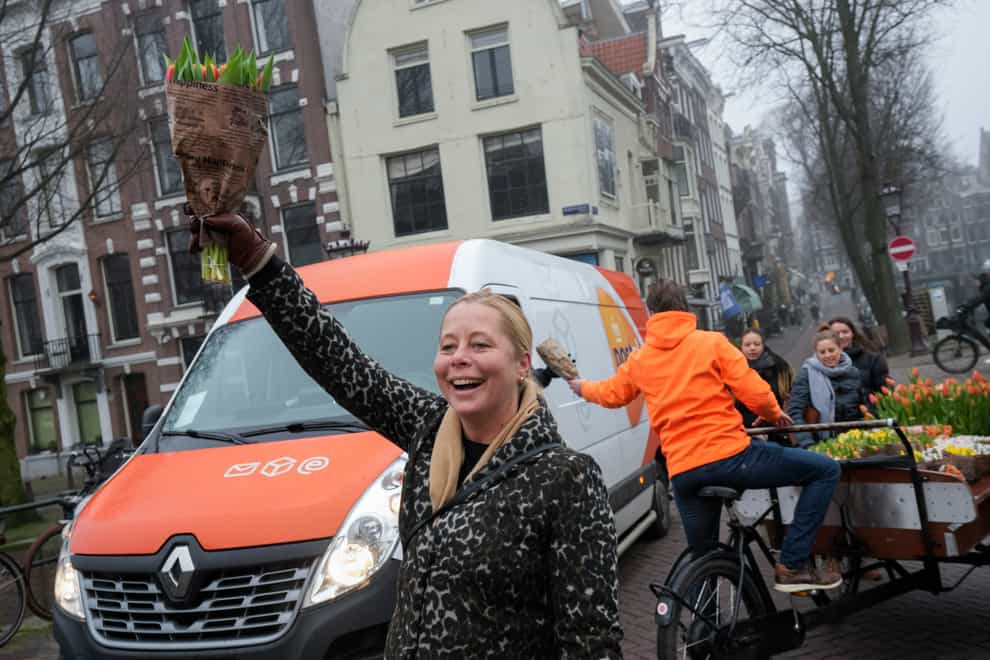 On the day stores in Amsterdam and across the Netherlands cautiously re-opened after weeks of coronavirus lockdown, the Dutch capital’s mood was further lightened by dashes of color in the form of thousands of free bunches of tulips handed out by growers in Amsterdam, Netherlands, Saturday, Jan. 15, 2022. (AP Photo/Peter Dejong)