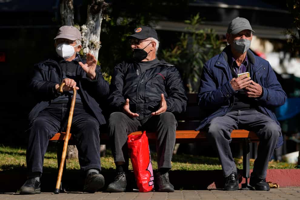Three elderly men wearing FFP2 face masks to curb the spread of coronavirus sit on a bench in Athens, Greece (Thanassis Stavrakis/AP)