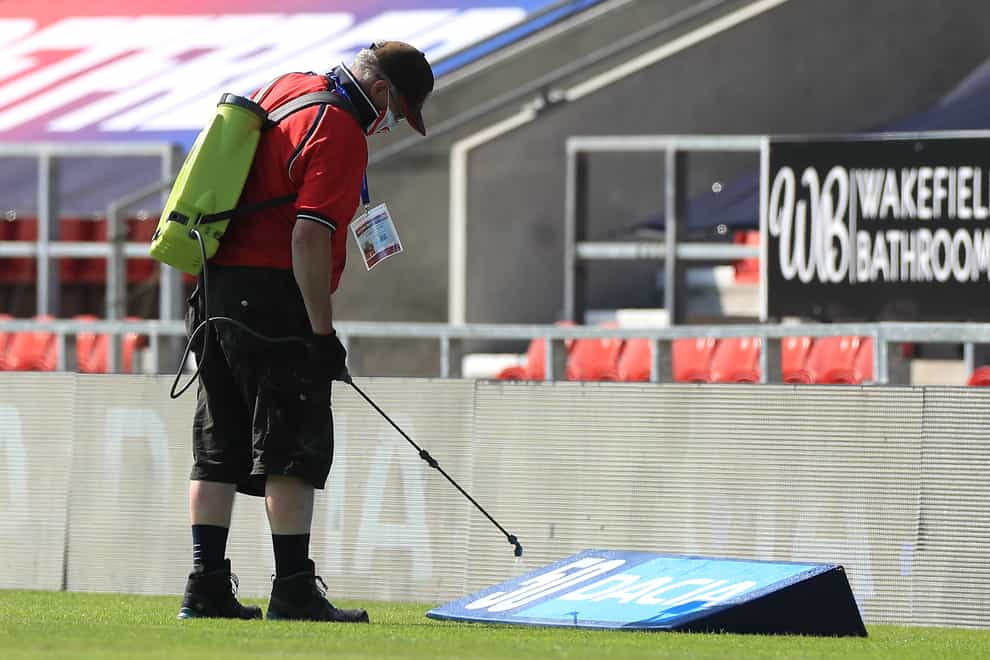 A ground staff member disinfects the area around the pitch before the Betfred Super League match at The Totally Wicked Stadium, St Helens.