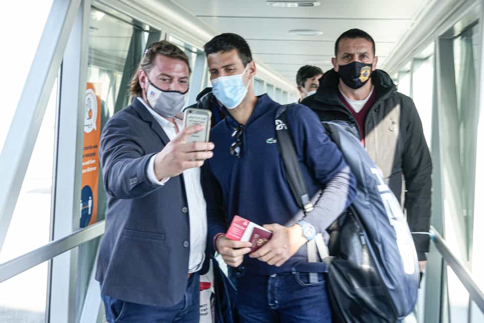 Novak Djokovic, centre, pauses for a picture after arriving back in Serbia (Darko Bandic/AP)
