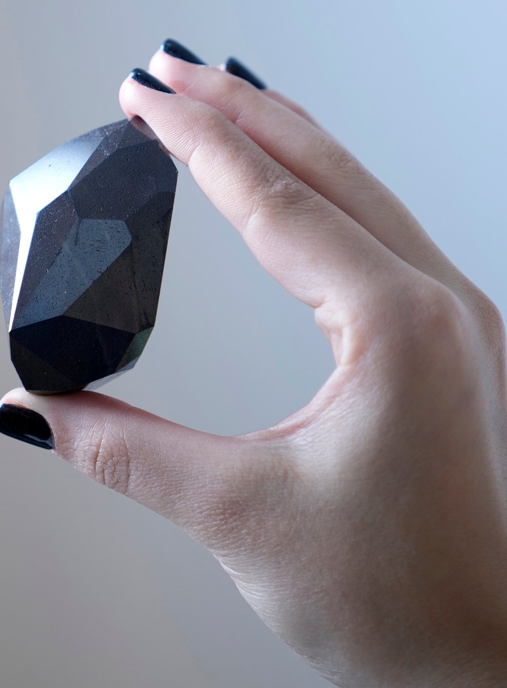 An employee of Sotheby’s Dubai presents a 555.55 carat black diamond (Kamran Jebreili/AP)