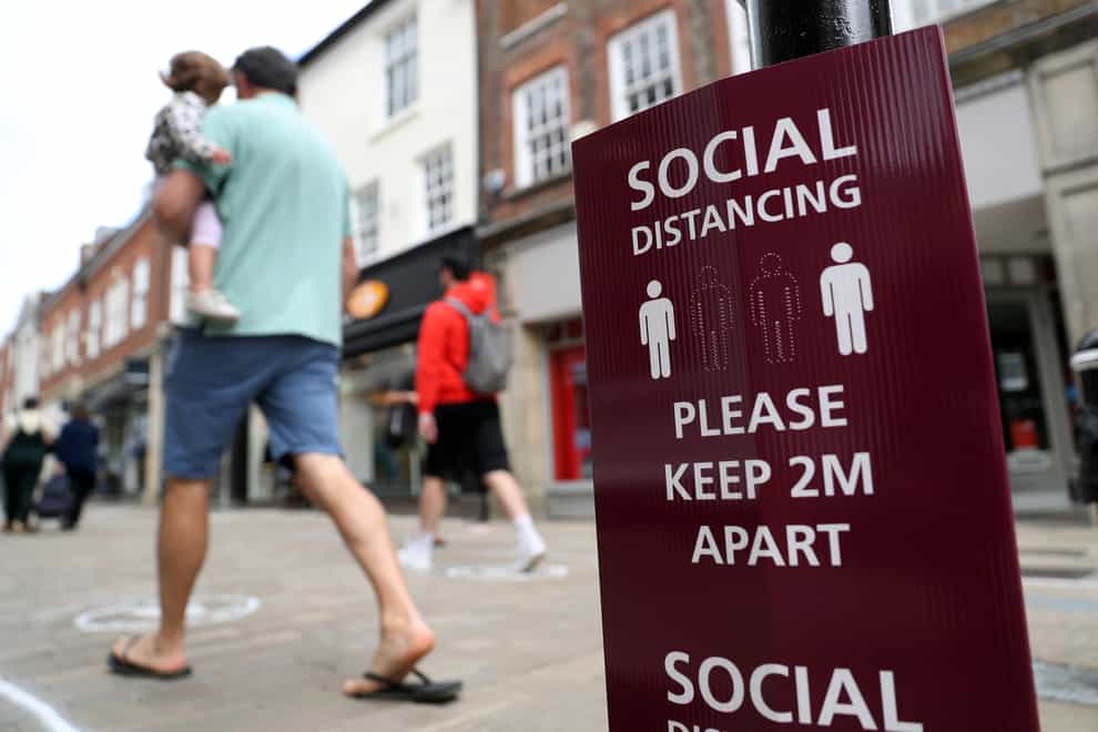People walk past a social distancing sign on the high street in Winchester (Andrew Matthews/PA)