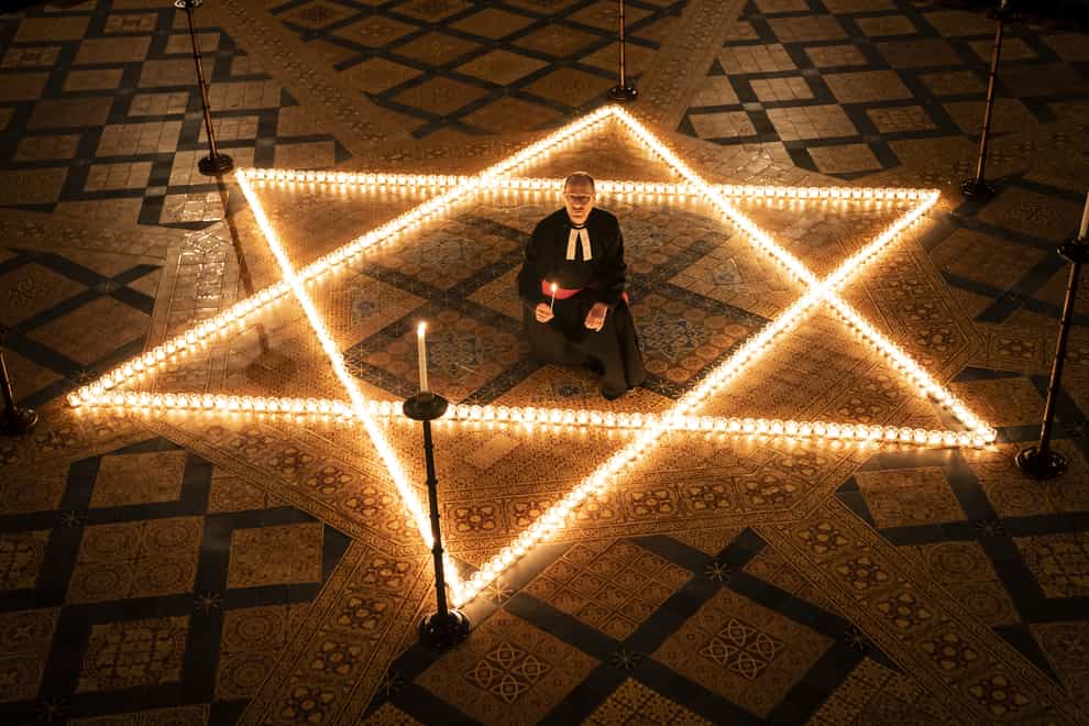 The Reverend Canon Michael Smith helps light six hundred candles in the shape of the Star of David (Danny Lawson/PA)