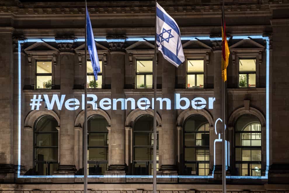 The lettering “#WeRemember” is on the facade of the Reichstag building in Berlin, Germany, Wednesday, Jan. 26, 2022. The light action is part of the international commemoration campaign of UNESCO and the World Jewish Congress. The two organizations launched the campaign in 2017 to commemorate the millions of Jews murdered under National Socialism. The words #WeRemember will shine on numerous buildings around the world until January 27. (Paul Zinken/dpa via AP)