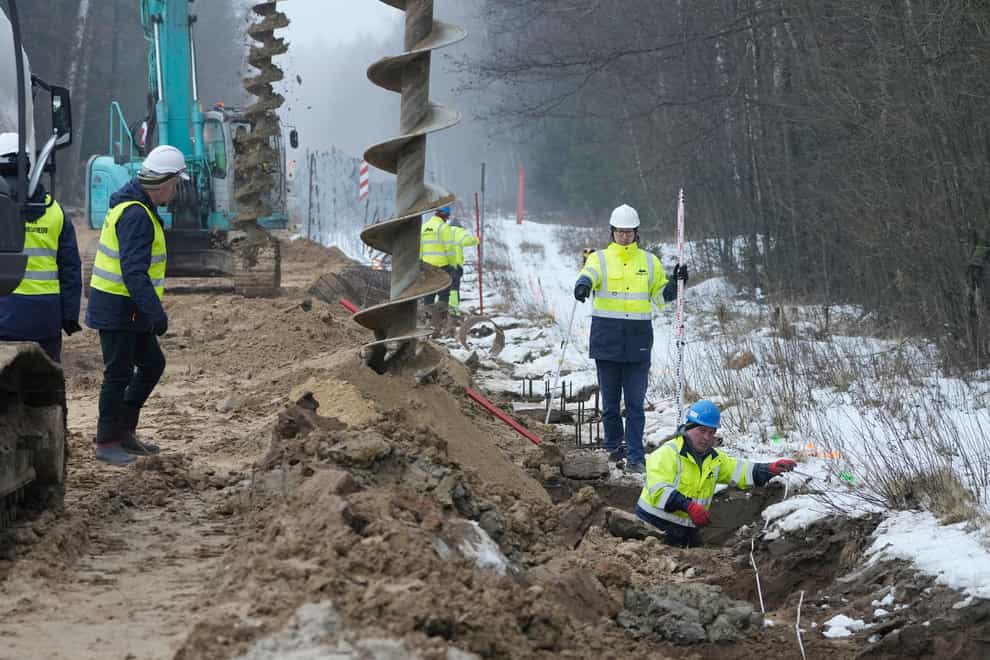 Workers and heavy machinery working on the first part of some 180 kilometers (115 miles) of a 5.5 meter (18ft)-high metal wall intended to block migrants pushed by Belarus, in what the European Union calls a “hybrid attack,” from crossing illegally into EU territory, in Tolcze, near Kuznica, Poland, on the Polish side of the border with Belarus on, Thursday, Jan. 27, 2022. (AP Photo/Czarek Sokolowski)