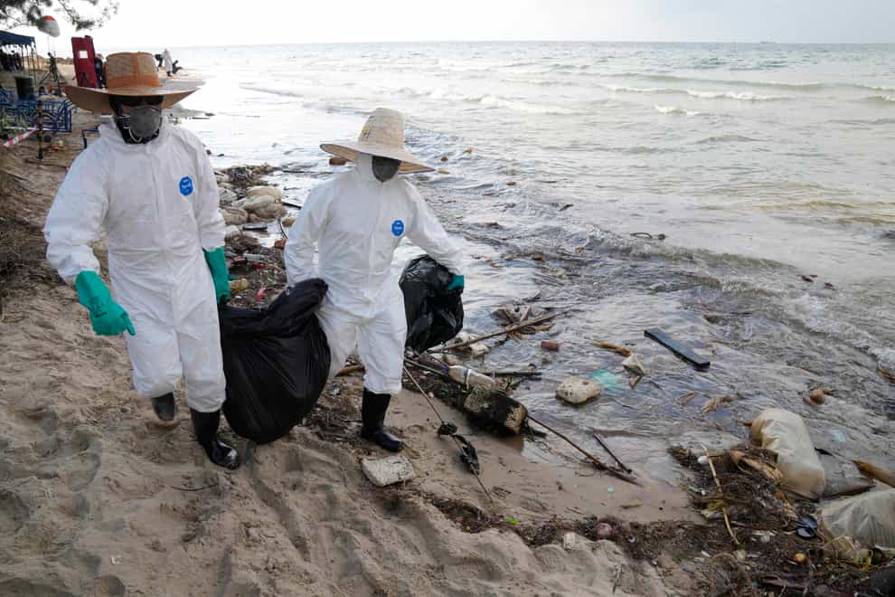 Workers carry out a clean-up operation on Mae Ramphueng Beach after a pipeline oil spill off the coast of Rayong province in eastern Thailand (Sakchai Lalit/AP)