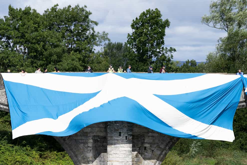 Supporters of Scottish independence hang a huge Saltire flag over the Auld Brig (Jane Barlow/PA)